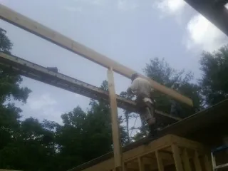 Carpenter setting a ridge beam over a new addition frame — Ice Dam Removal by Roofing Brothers in Lenore