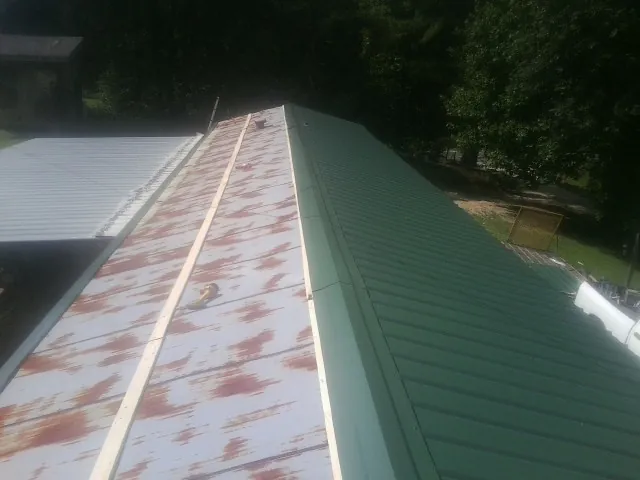 Old rusted panels beside newly installed green metal roofing — Wind Damage Roof Repair by Roofing Brothers in Lenore
