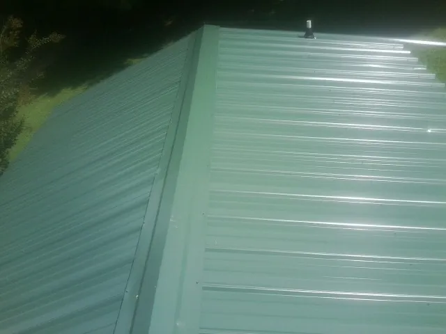 New green metal panels meeting at the ridge of a roof — Flat Roof Repair work by our crew in Lenore