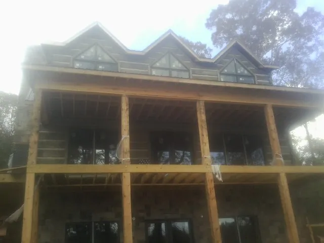 Dormers and porch framing on a large log home under construction — Roof Coating work by our crew in Lenore