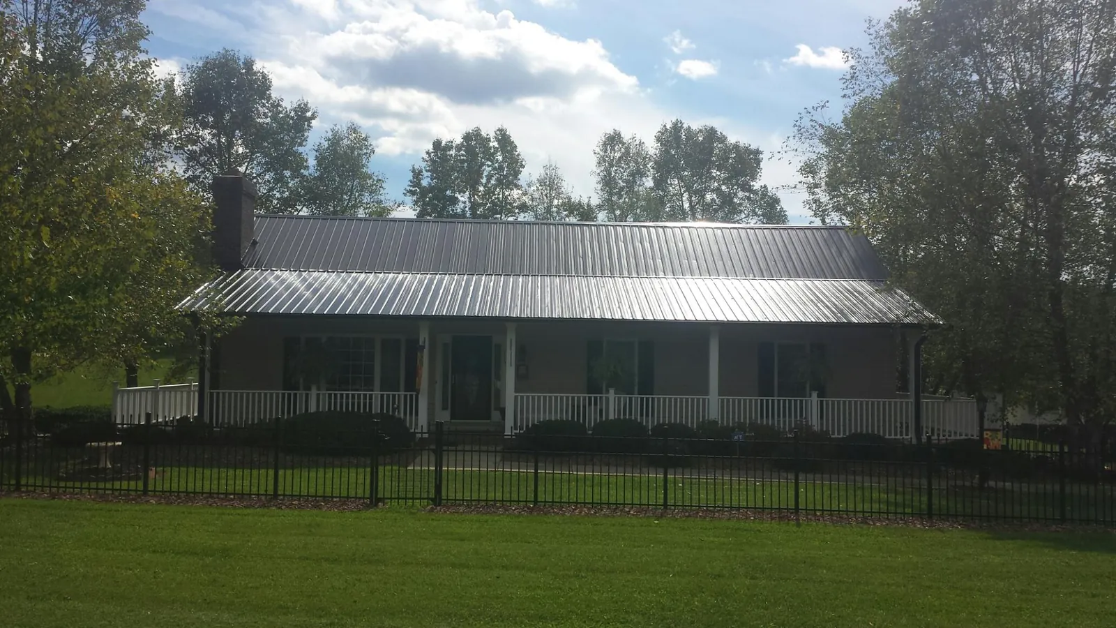 Gray metal roof on a brick ranch with a full width front porch — Gutter Guard Installation work by our crew in Lenore