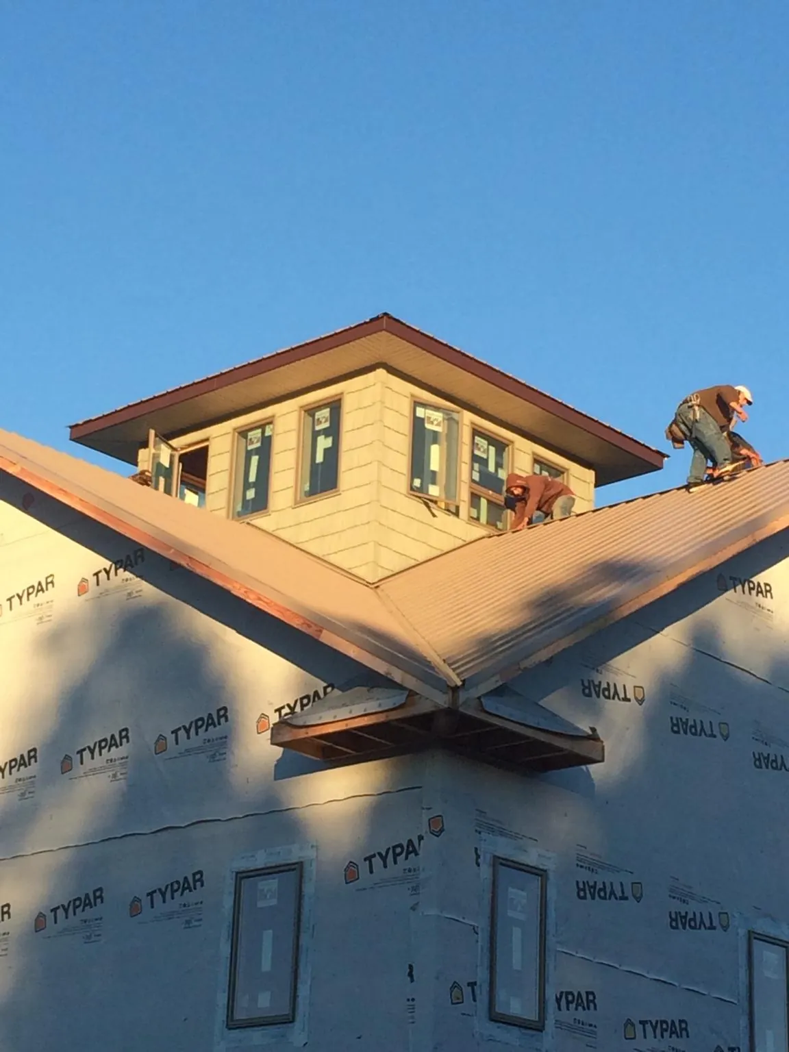 Roofers working around a rooftop cupola on a new metal roof at sunset — Roof Waterproofing in Lenore by Roofing Brothers